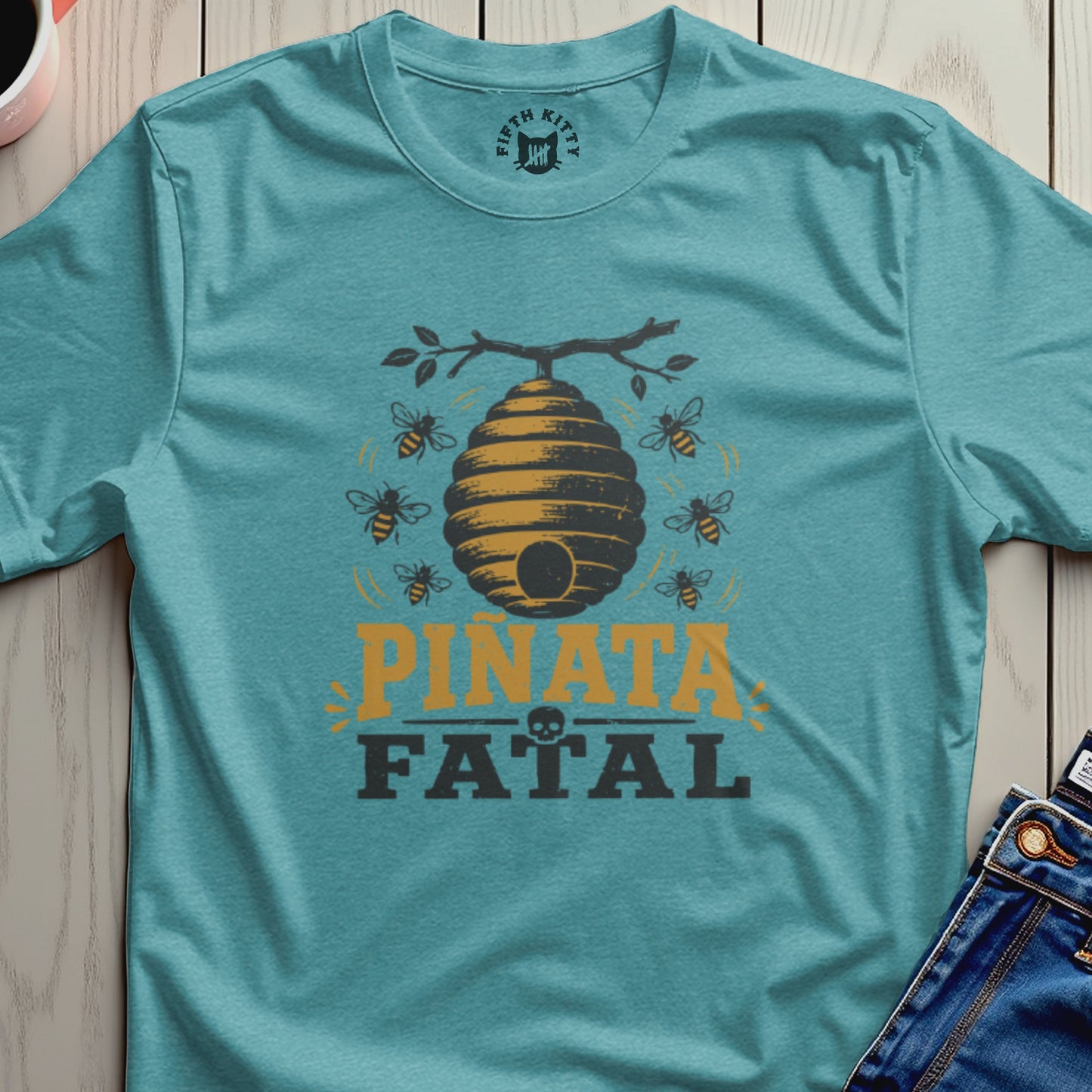 Teal t-shirt with beehive, bees, and text "PIÑATA FATAL" graphic.