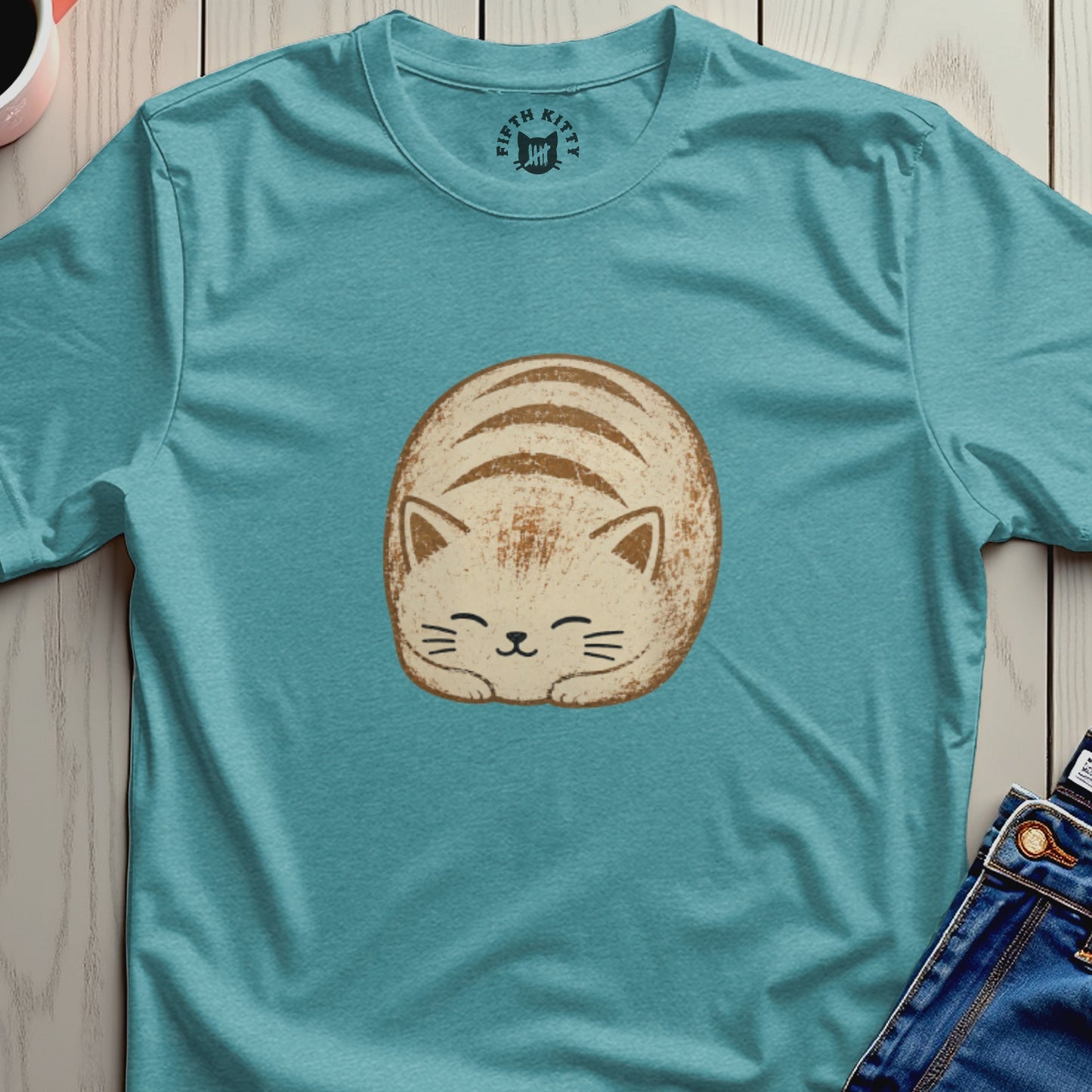 Teal t-shirt with a round, cartoon-style cat sleeping on it.