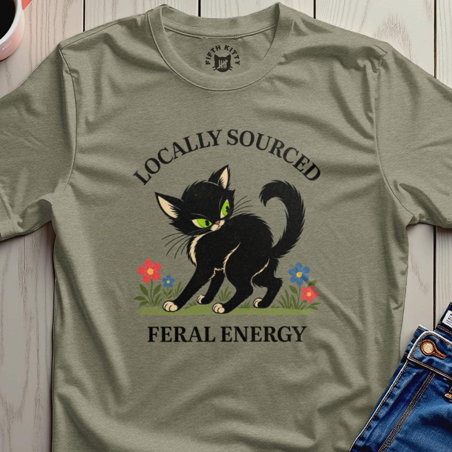 Black cat with green eyes, "Locally Sourced Feral Energy" text, and flowers on a t-shirt.