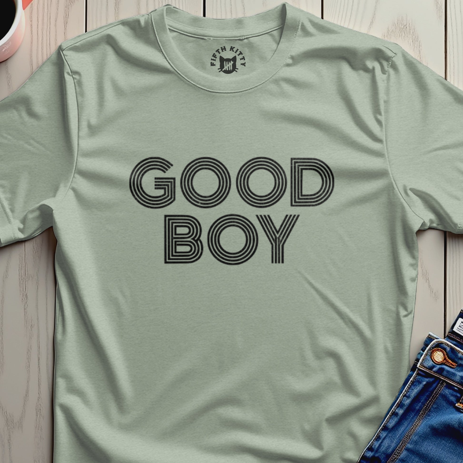 Light sage t-shirt with black text "GOOD BOY" in stacked, striped letters.