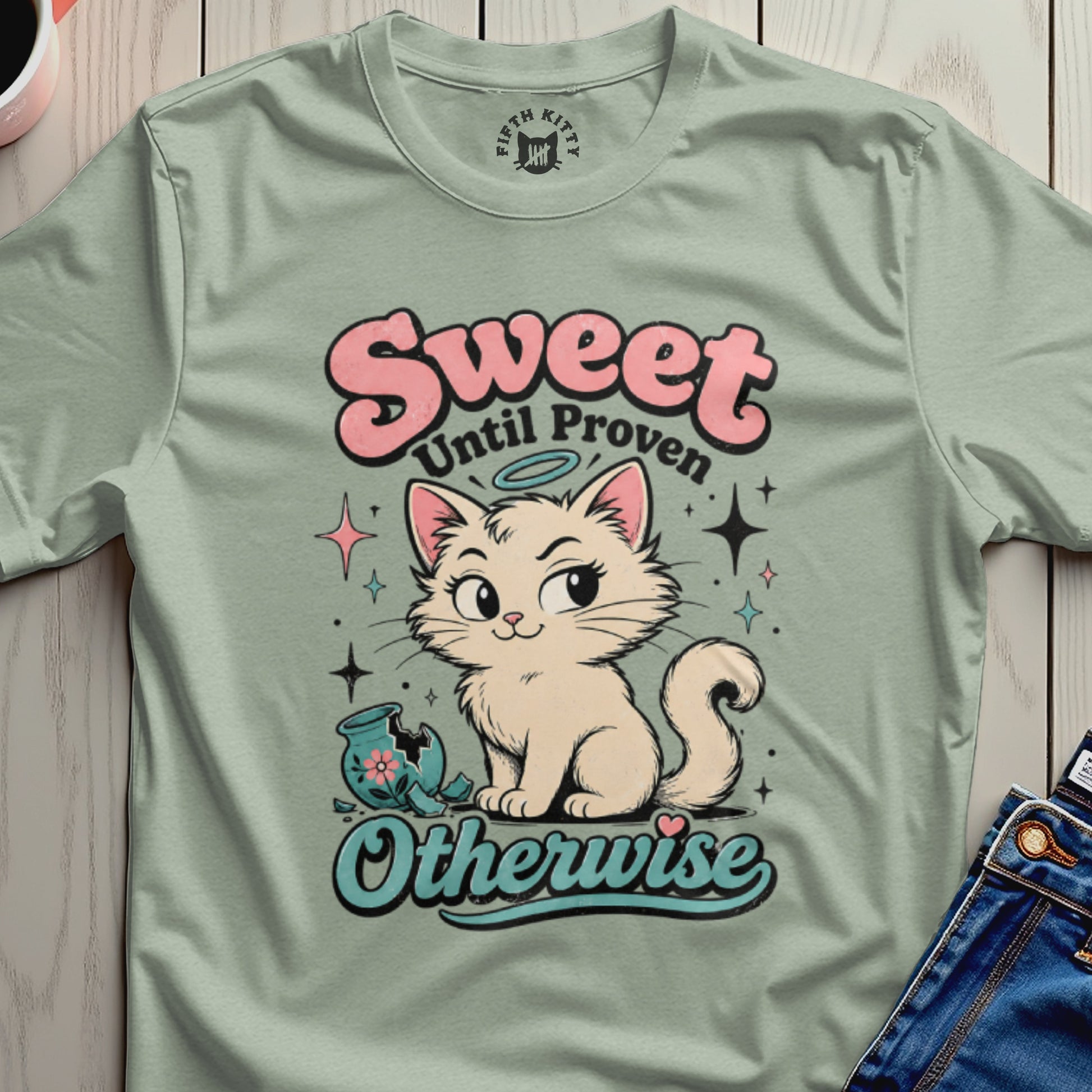 Light green t-shirt with a cream cat, broken vase, and text "Sweet Until Proven Otherwise".