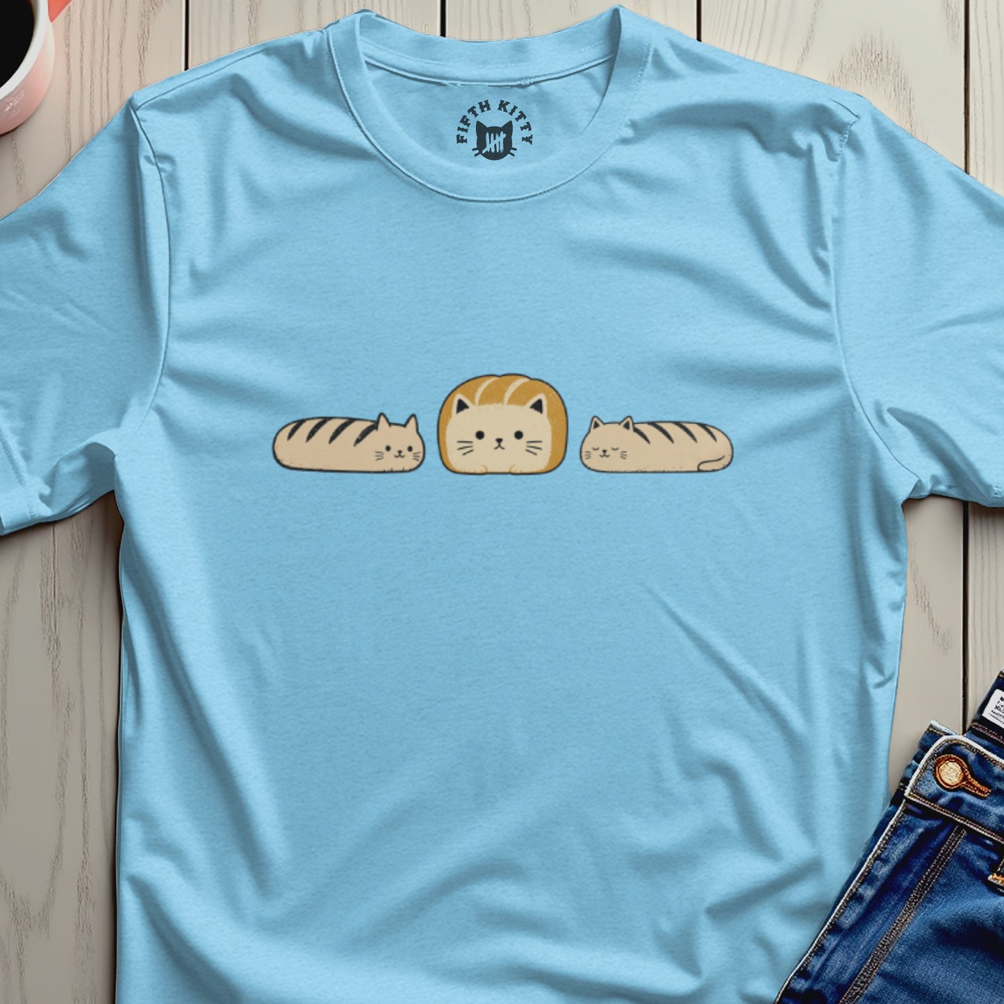 Light blue t-shirt with a graphic of three cats resembling loaves of bread.