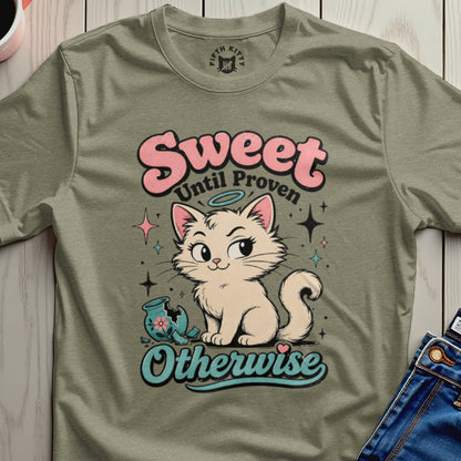 Cream cat with halo and broken vase graphic on a green t-shirt.