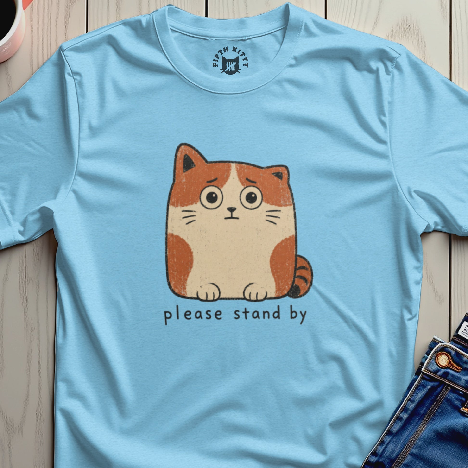 Light blue t-shirt with anxious cat graphic and "please stand by" text.