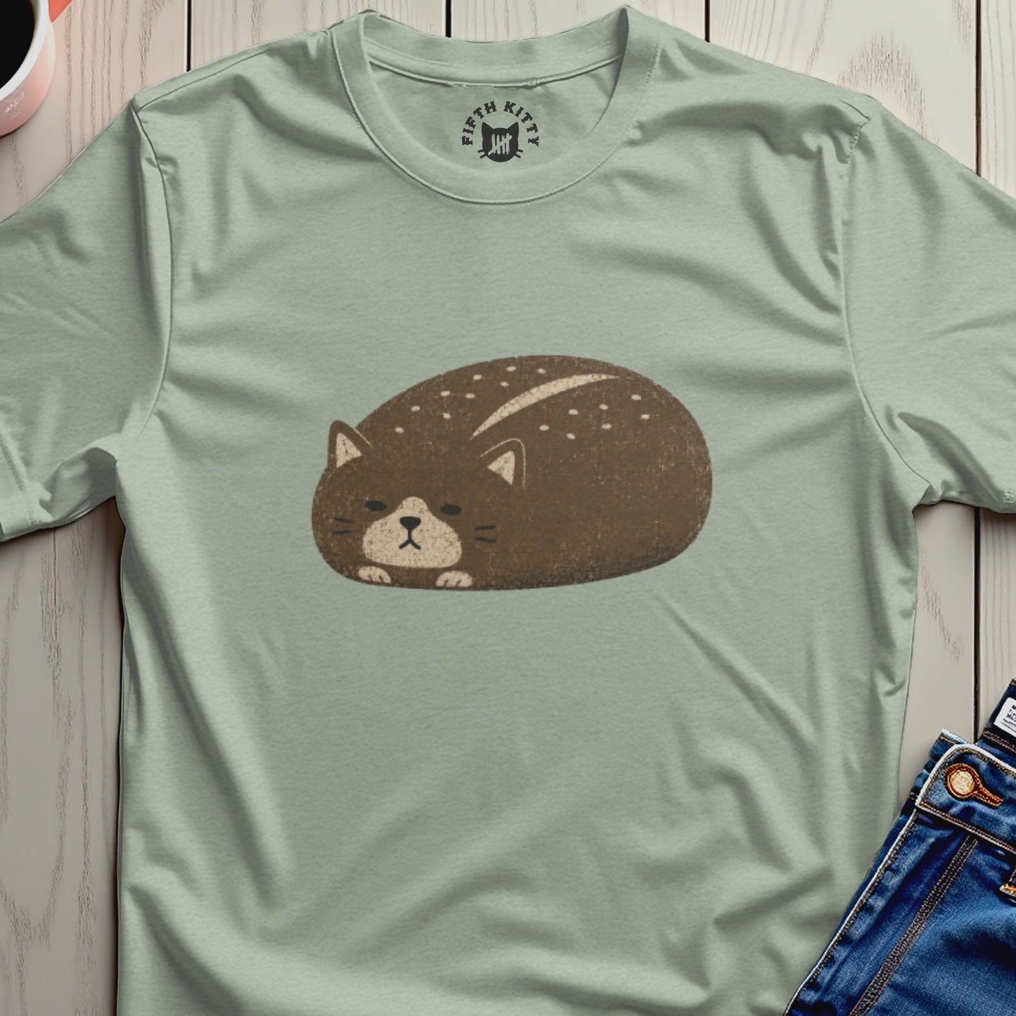 Light green t-shirt with a round, brown cat graphic with white speckles.