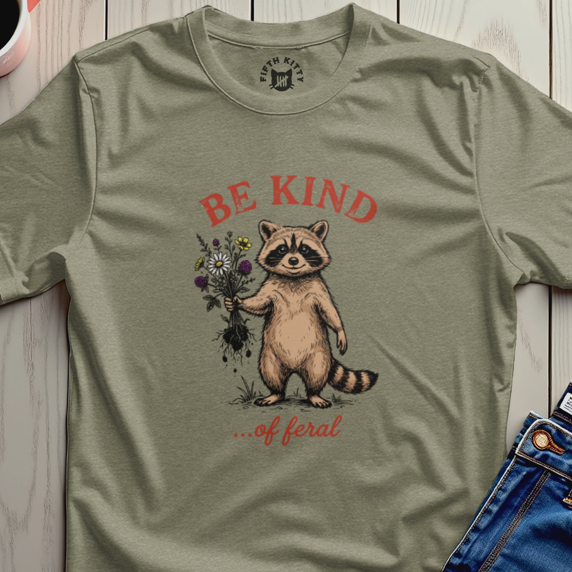 Raccoon holding flowers with "BE KIND ...of feral" text.