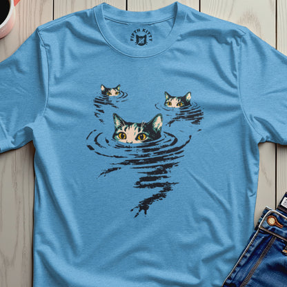Three cats' faces peek from rippling water on a blue t-shirt.