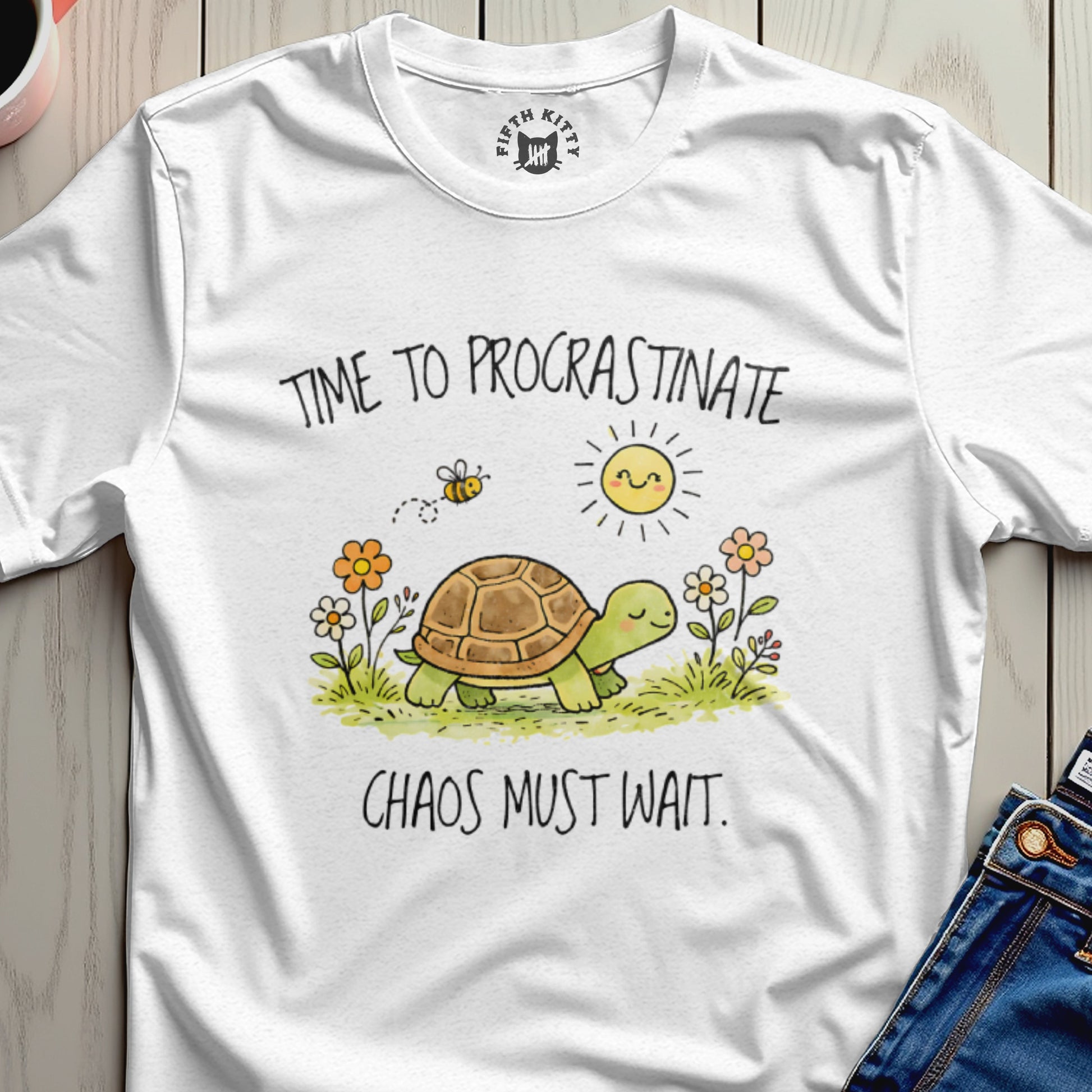 White t-shirt with a turtle, bee, sun, and flowers. Text: TIME TO PROCRASTINATE. CHAOS MUST WAIT.