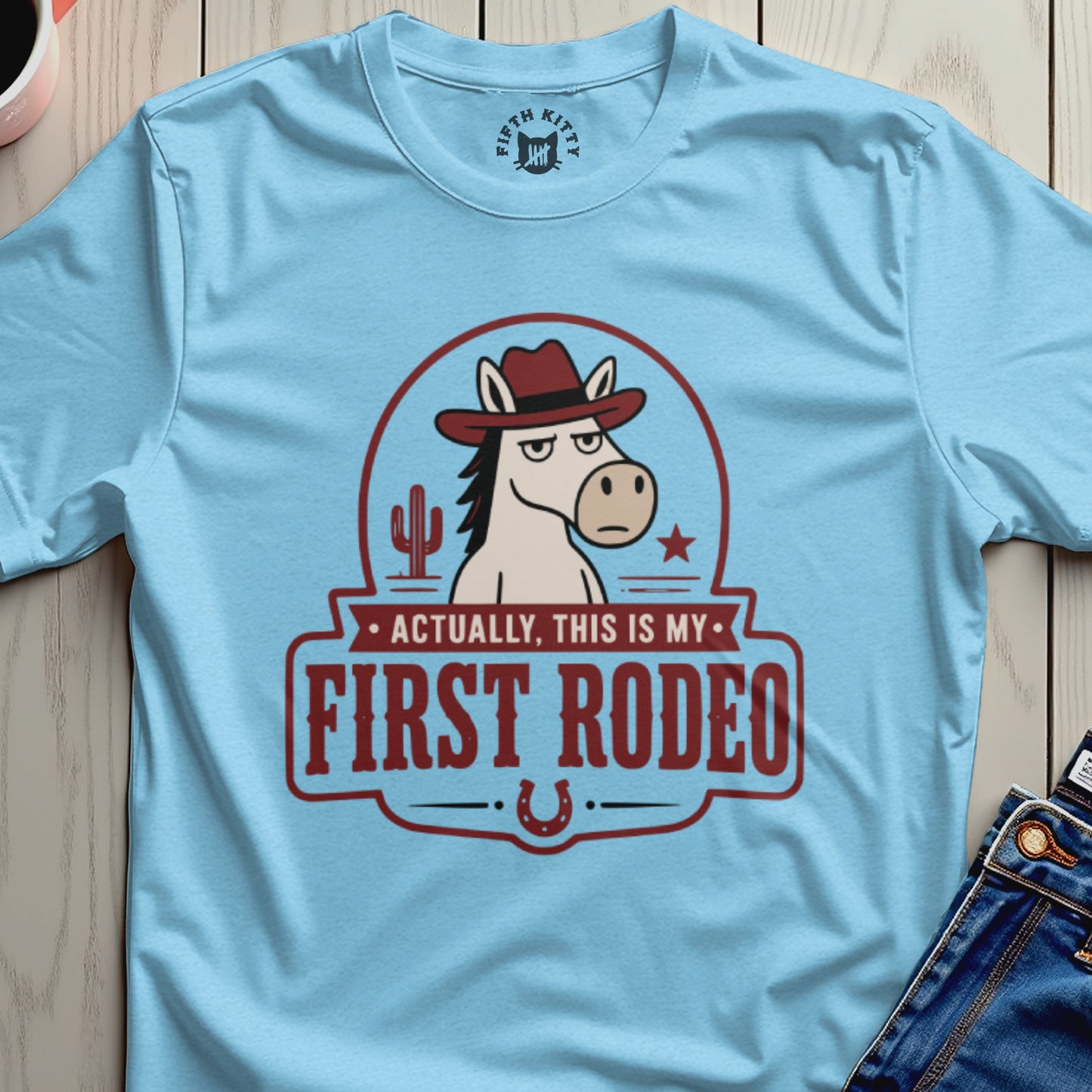 Light blue t-shirt with cartoon horse wearing cowboy hat and text "Actually, this is my first rodeo."