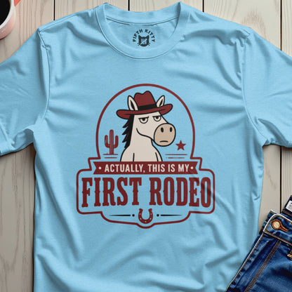 Light blue t-shirt with cartoon horse wearing cowboy hat and text "Actually, this is my first rodeo."