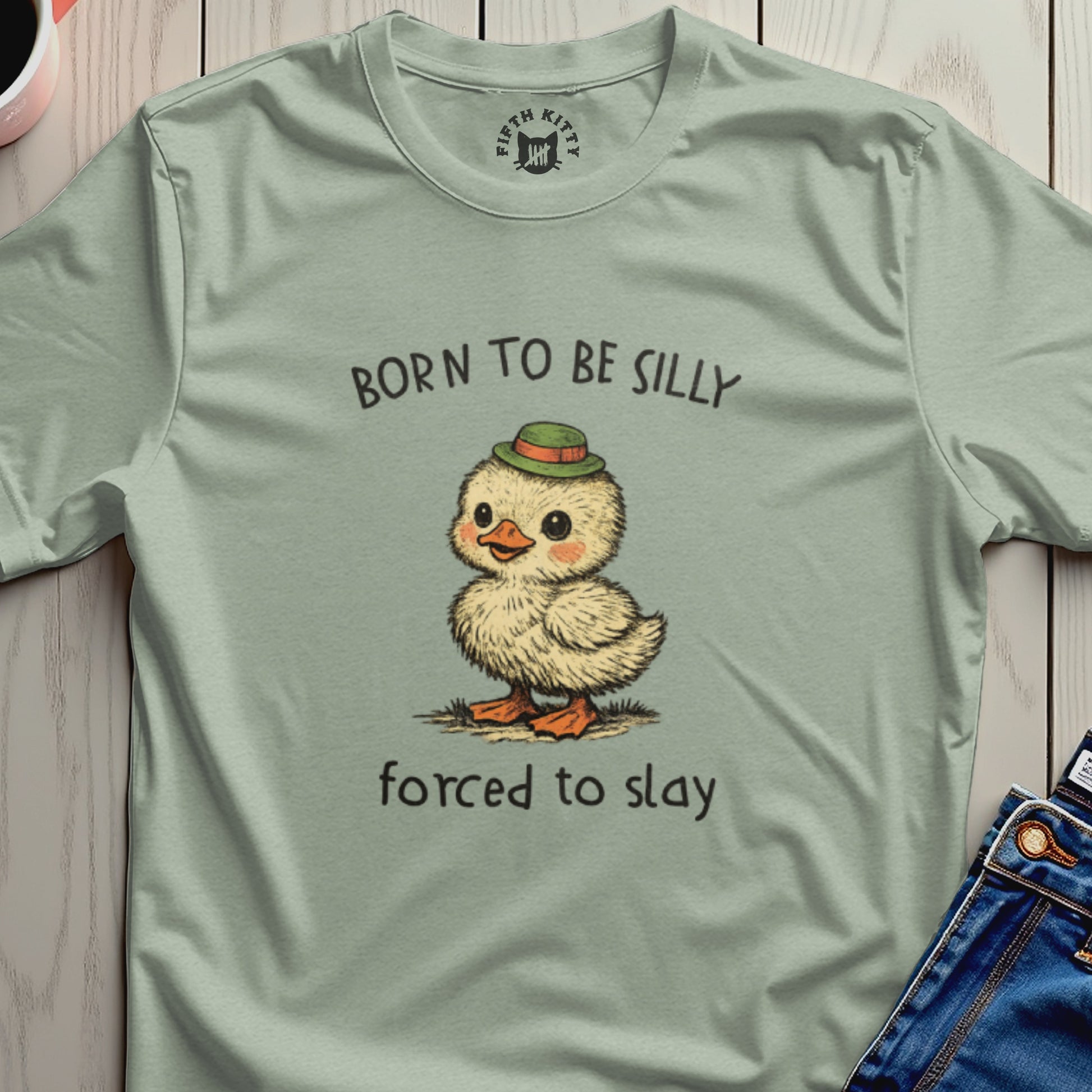 Cartoon chick wearing a green hat, "BORN TO BE SILLY FORCED TO SLAY" text.