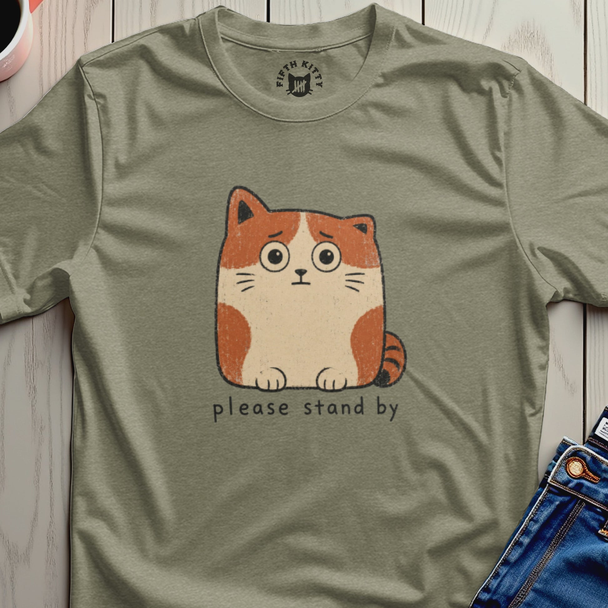T-shirt with a drawing of a worried cat and the text "please stand by".