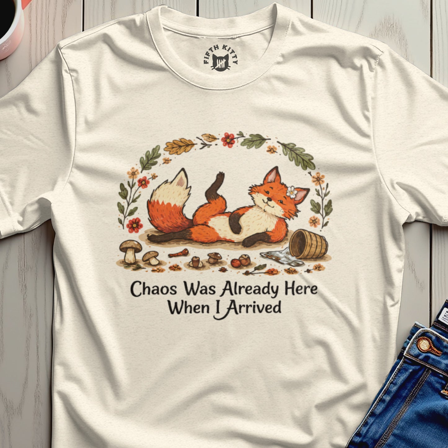 Cream t-shirt with a graphic of a whimsical fox, mushrooms, and leaves with text.