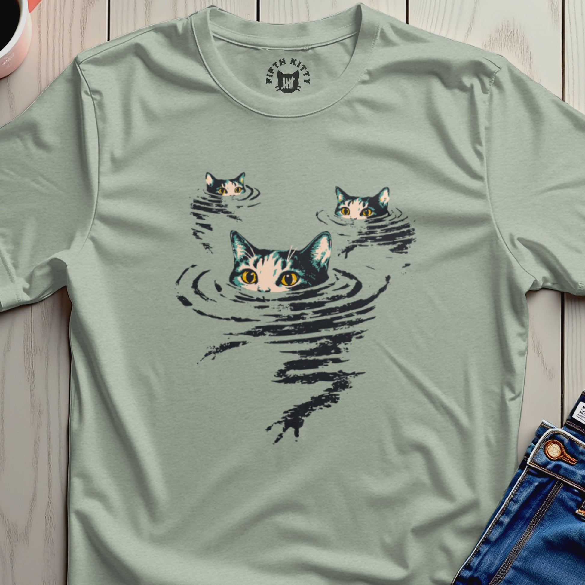 Three cats peeking out of dark water on a light green t-shirt.