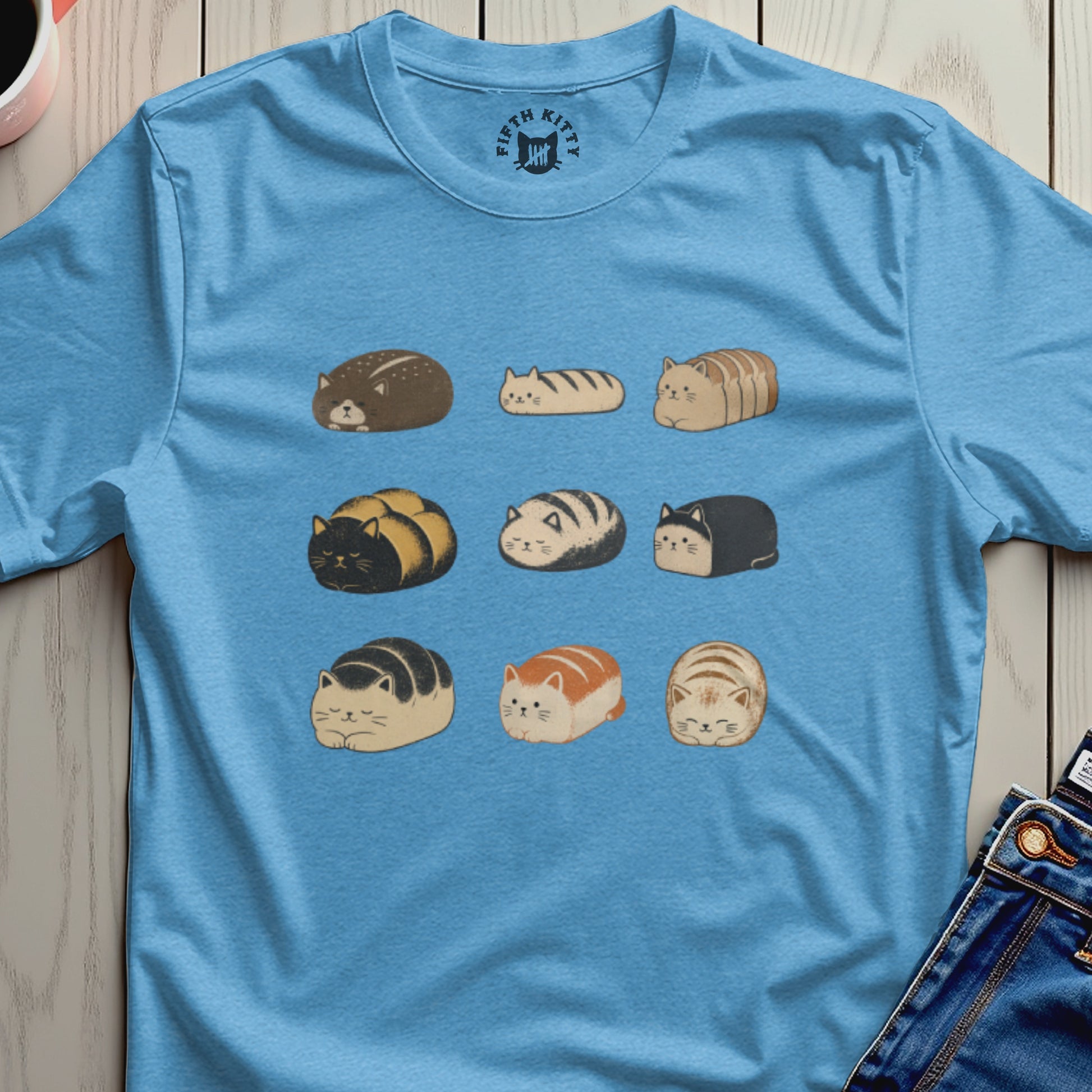 Blue t-shirt with a repeating pattern of cartoon loaf cats in nine different colors and styles.