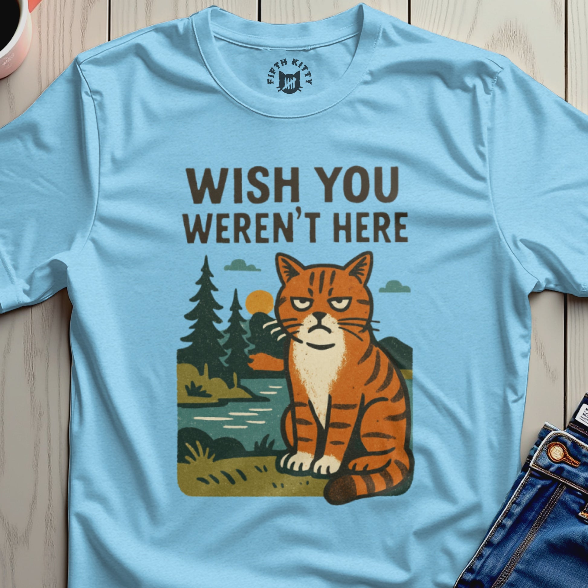 Light blue t-shirt with a grumpy cat, trees, and river graphic saying "Wish You Weren't Here".