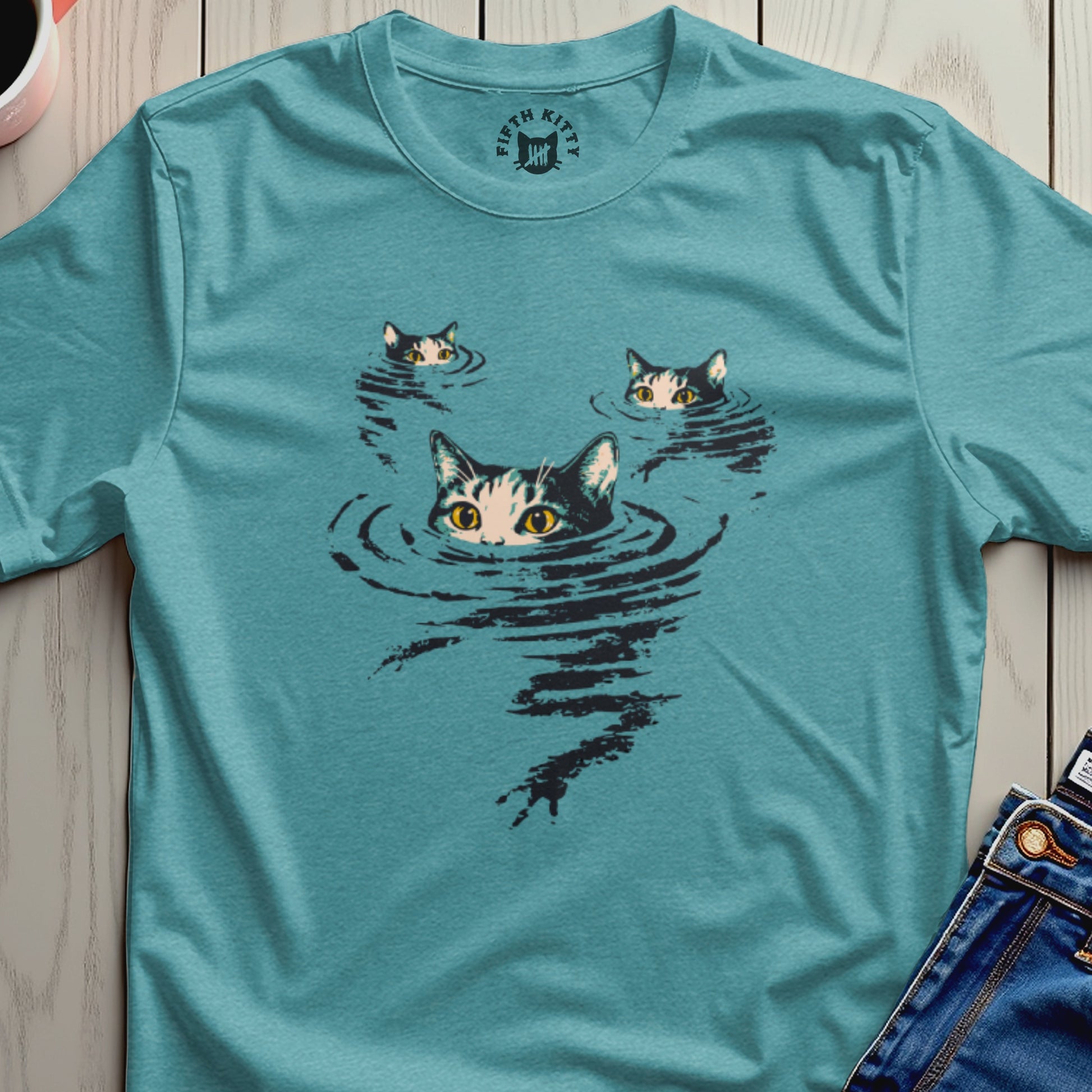 Three cats with wide eyes peer from dark water on a teal t-shirt.