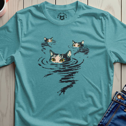 Three cats with wide eyes peer from dark water on a teal t-shirt.