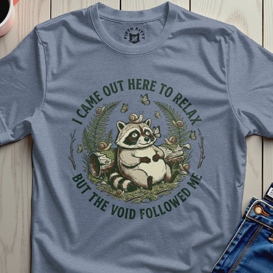 T-shirt with raccoon illustration and text "I came out here to relax but the void followed me".