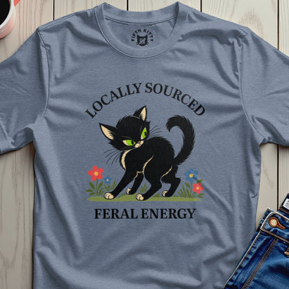 Black cat with green eyes on a blue t-shirt, "Locally Sourced Feral Energy."