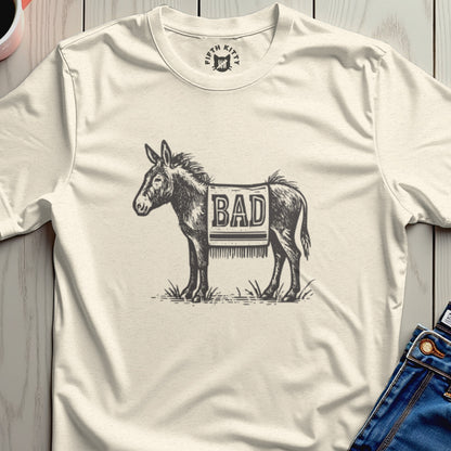 Cream t-shirt with a drawing of a donkey wearing a patterned blanket with "BAD" written on it.