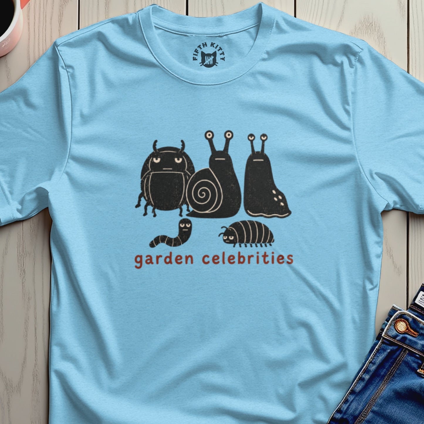 Light blue t-shirt with a graphic of black cartoon bugs and snails, reading "garden celebrities".