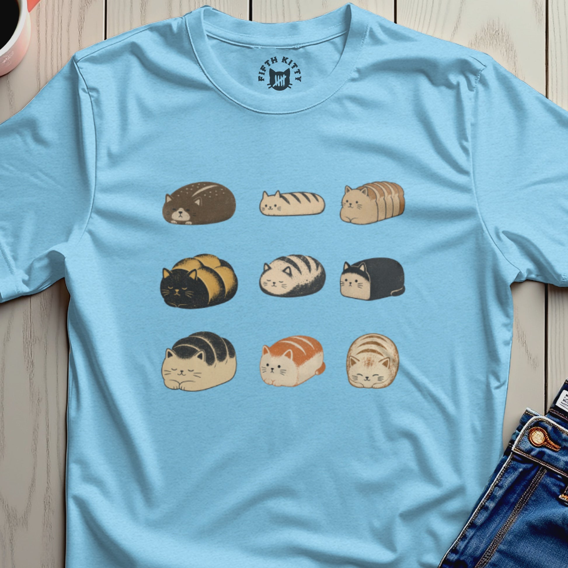 Light blue t-shirt with a grid of nine cartoon cat loaves in various colors and patterns.