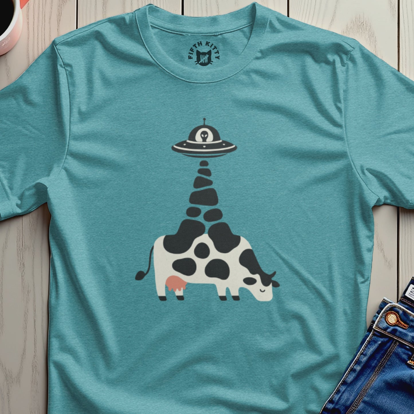 Teal t-shirt with a graphic of a cow being abducted by a UFO.