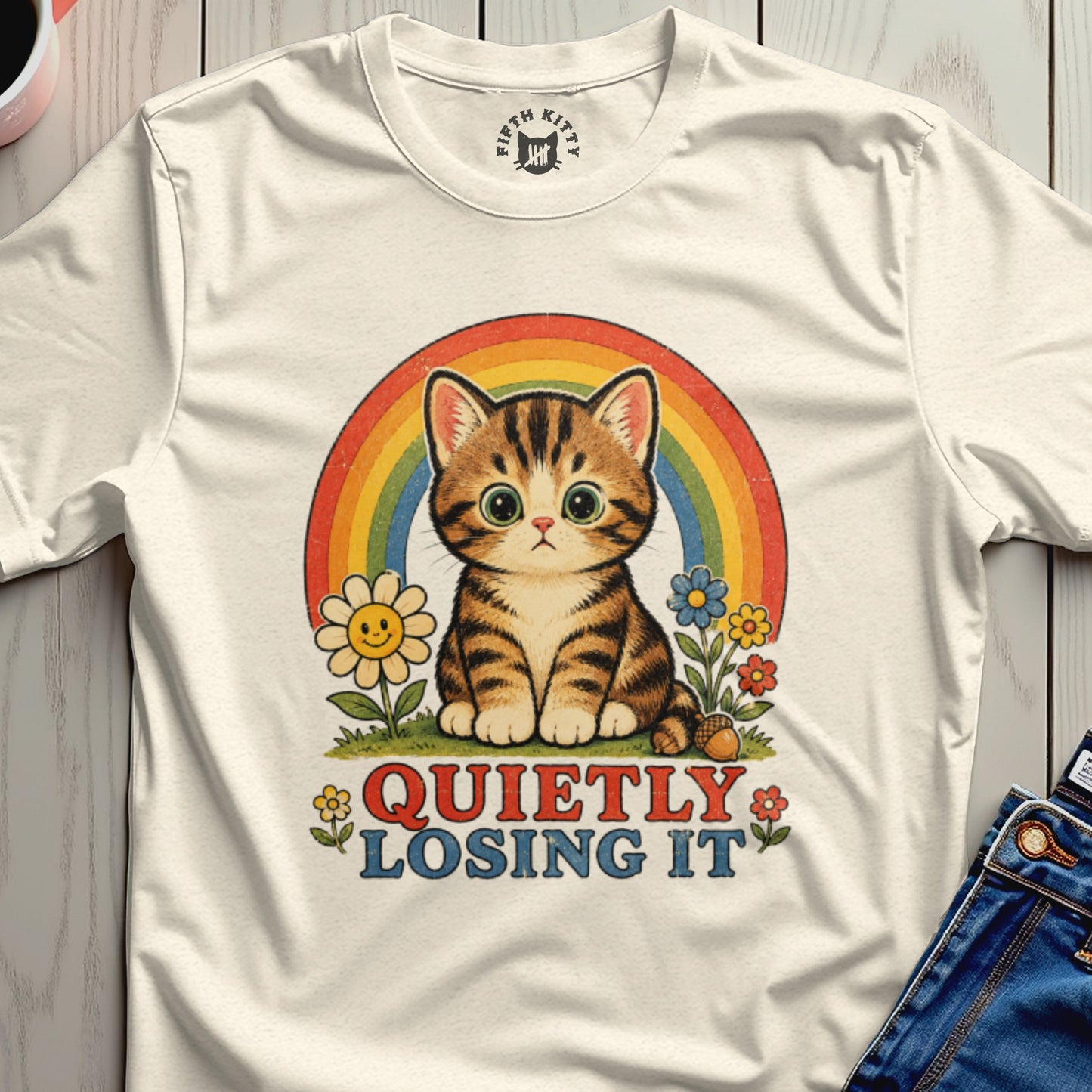 Cream t-shirt with a retro graphic of a tabby cat, rainbow, and flowers with text "QUIETLY LOSING IT".