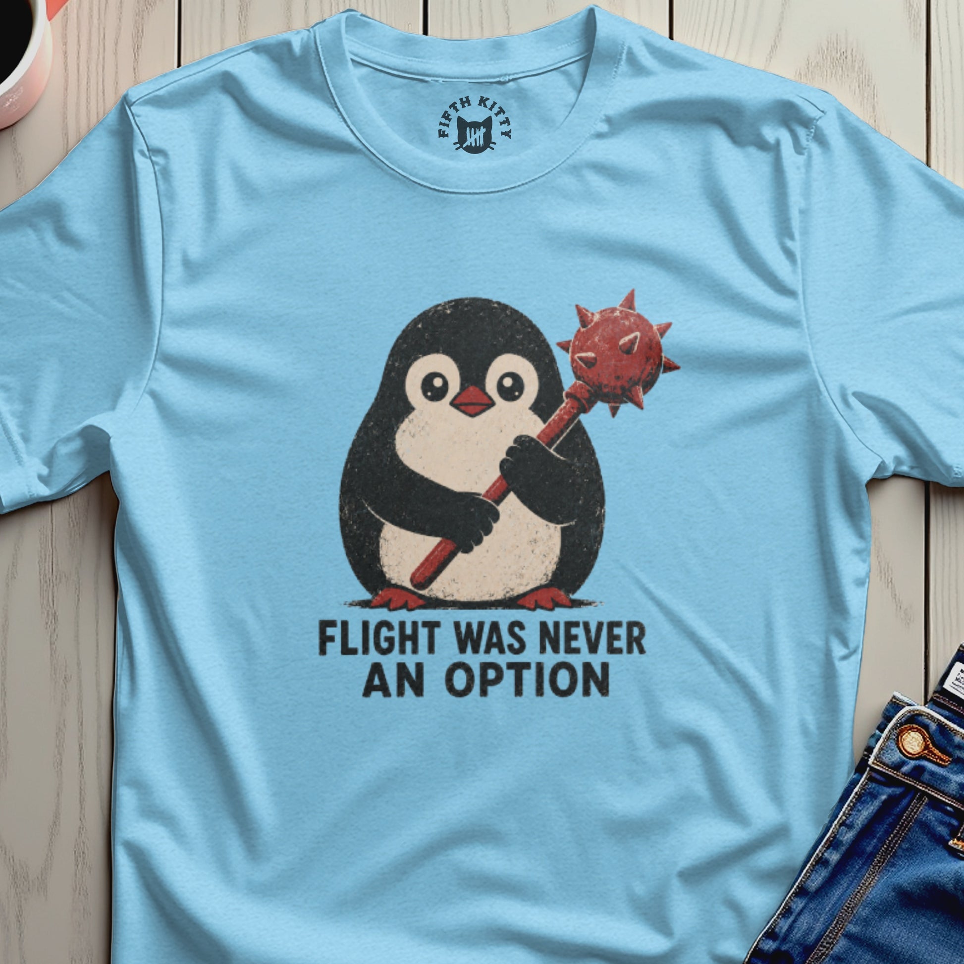 Light blue t-shirt with penguin holding mace and text "FLIGHT WAS NEVER AN OPTION".