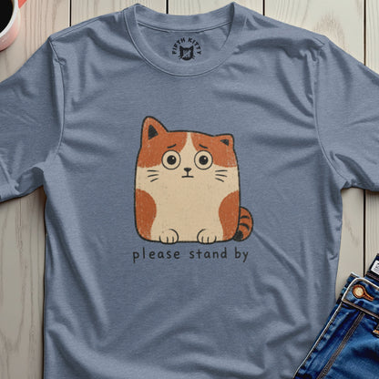 Blue t-shirt with anxious cartoon cat graphic saying "please stand by"