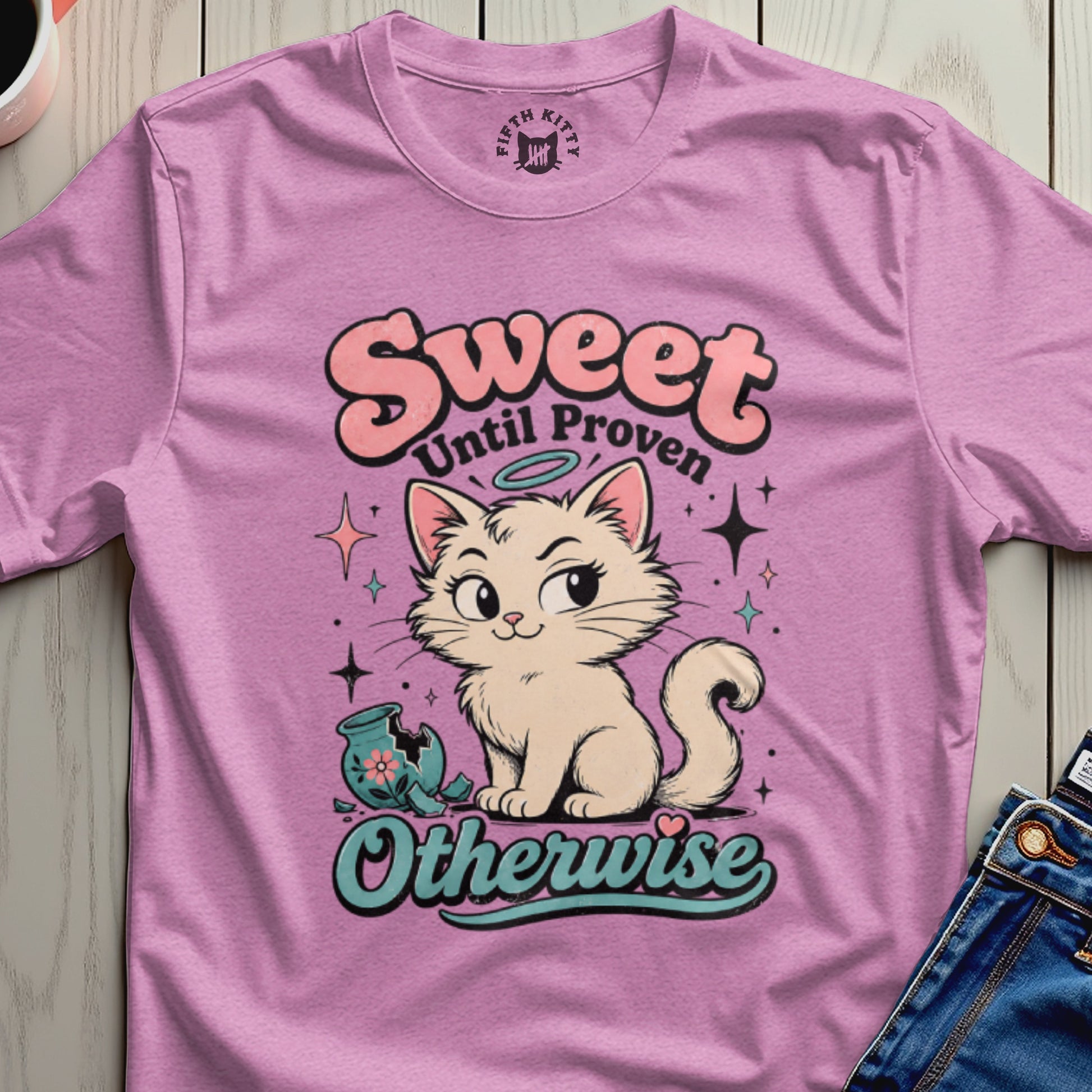 Pink t-shirt with a cream cat, broken vase, and "Sweet Until Proven Otherwise" text.