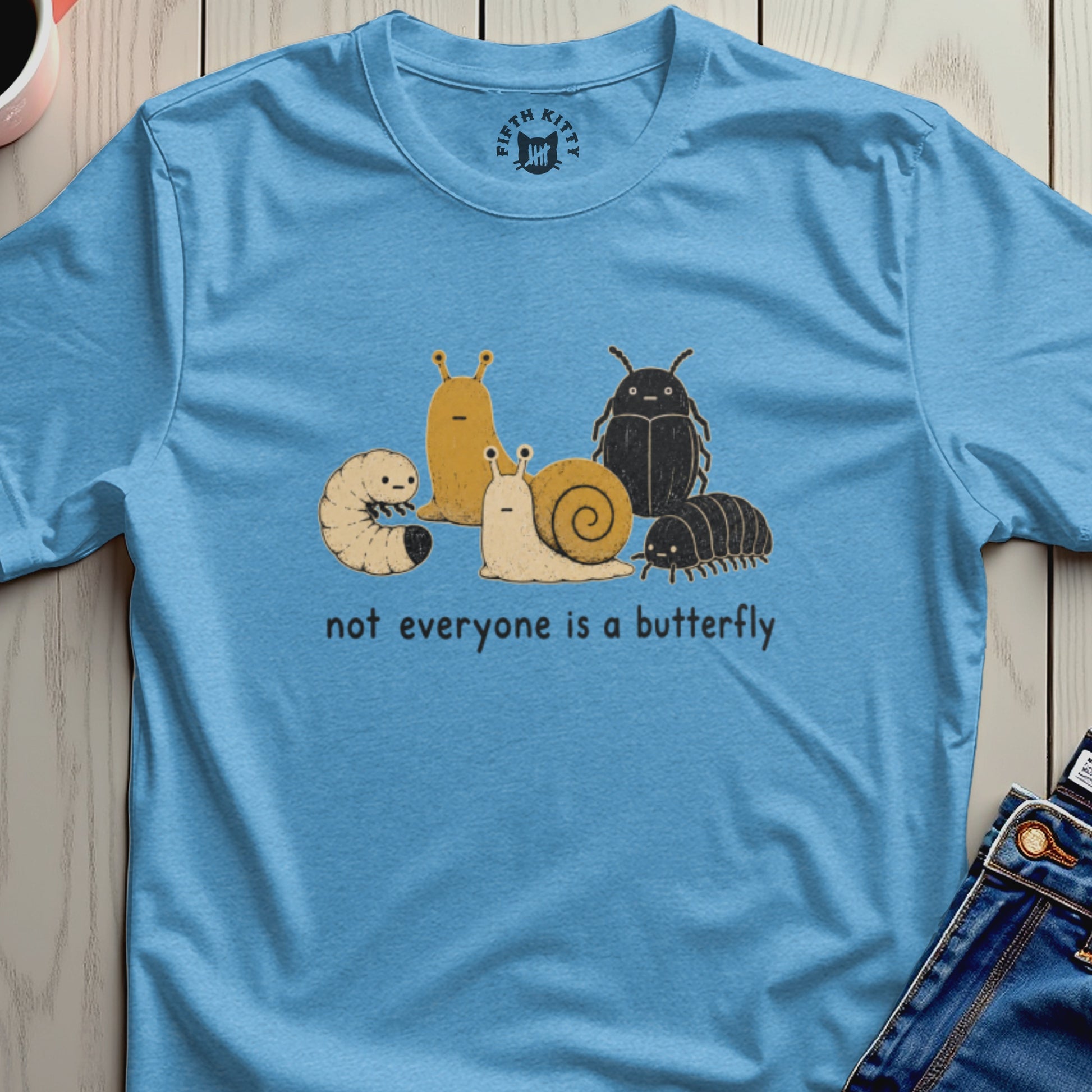Light blue t-shirt with cartoon insects and the text "not everyone is a butterfly".