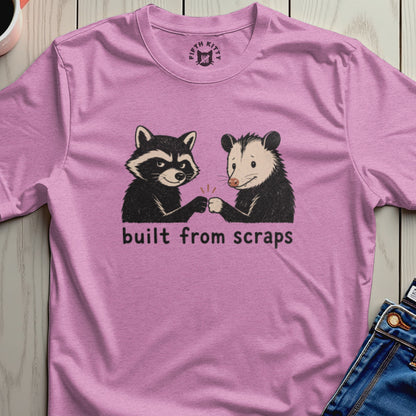 Pink t-shirt with racoon and opossum fist bumping, text reads "built from scraps".