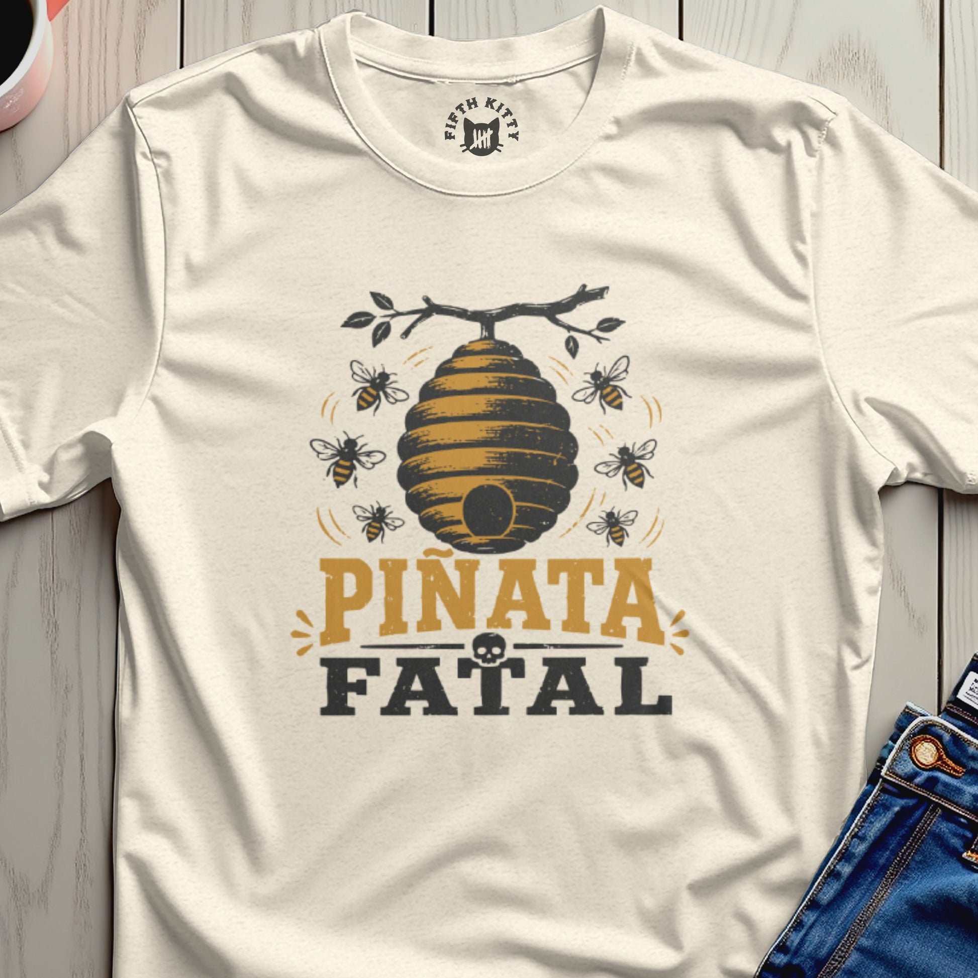 T-shirt with beehive graphic, bees, and "Piñata Fatal" text.