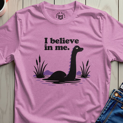 Pink t-shirt with a purple design of a Loch Ness Monster and the text "I believe in me."