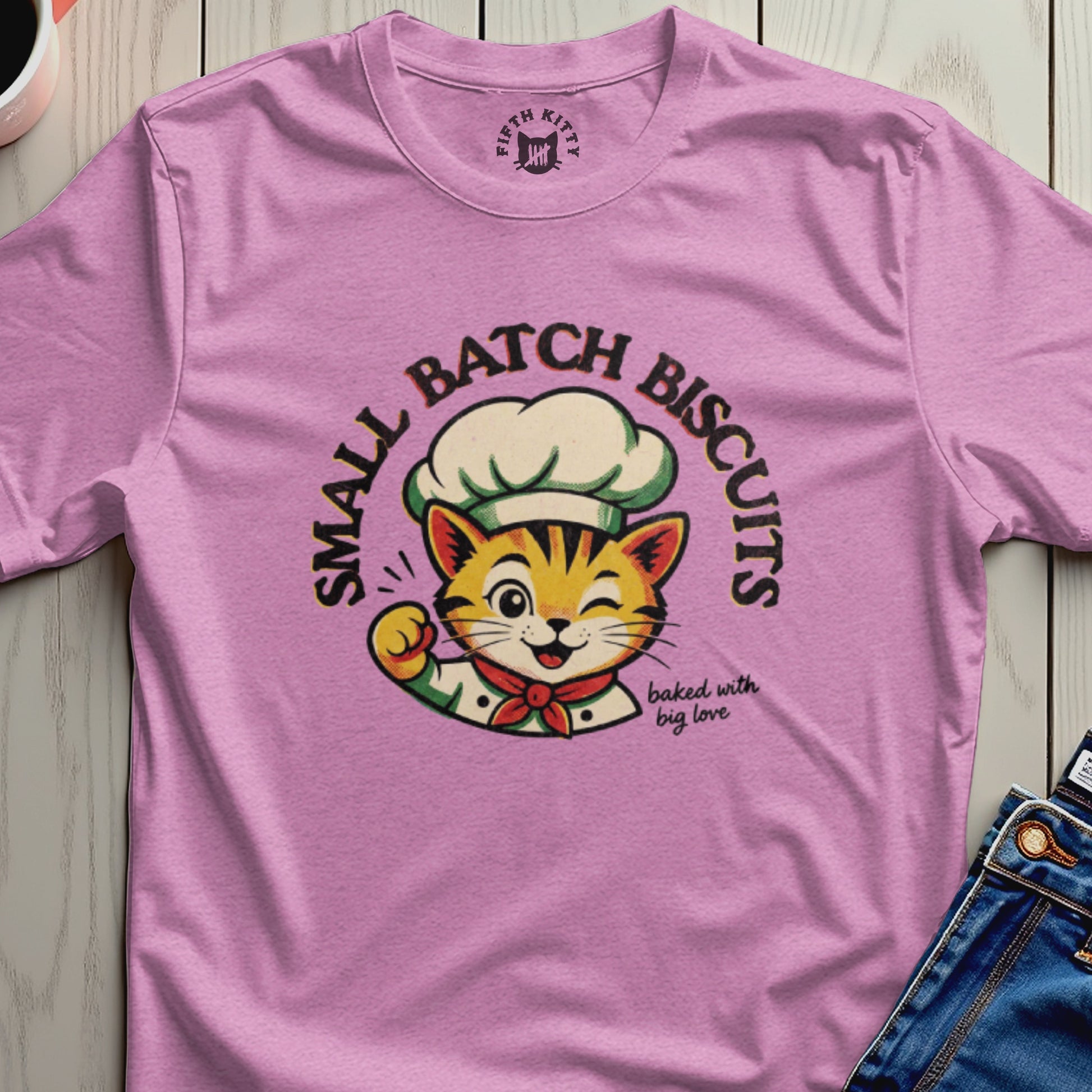 Pink t-shirt with a cartoon cat chef that says "Small Batch Biscuits" and "baked with big love".