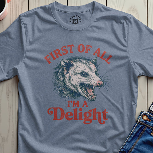 Blue t-shirt with vintage distressed graphic reading "First of all I'm a Delight" and a possum.