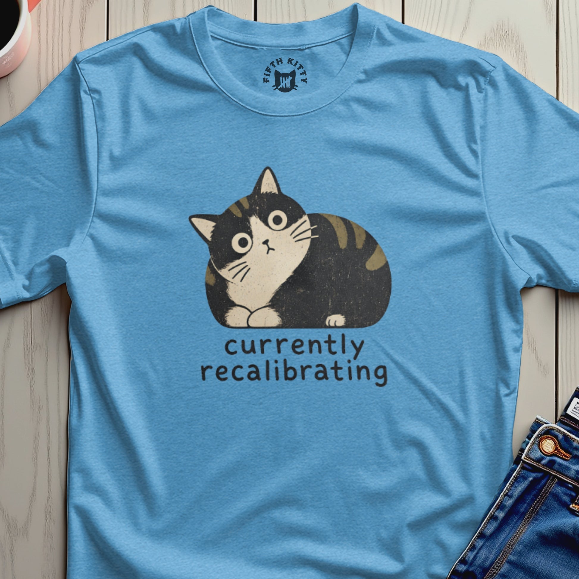 Blue t-shirt with a cartoon cat and text currently recalibrating.