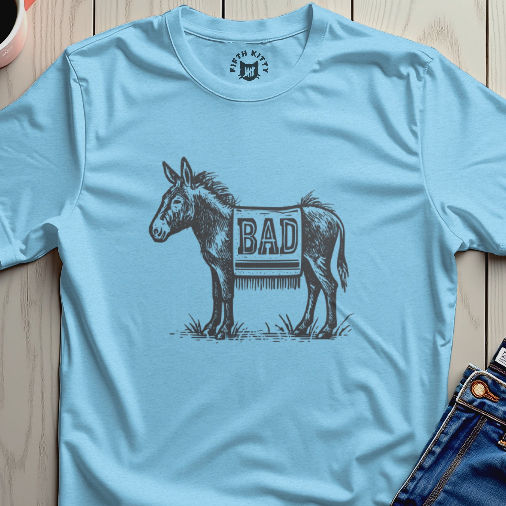 Donkey wearing a blanket that says "BAD" on a light blue t-shirt.