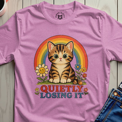 Pink t-shirt with a cartoon cat, rainbow, flowers, and the text "QUIETLY LOSING IT."