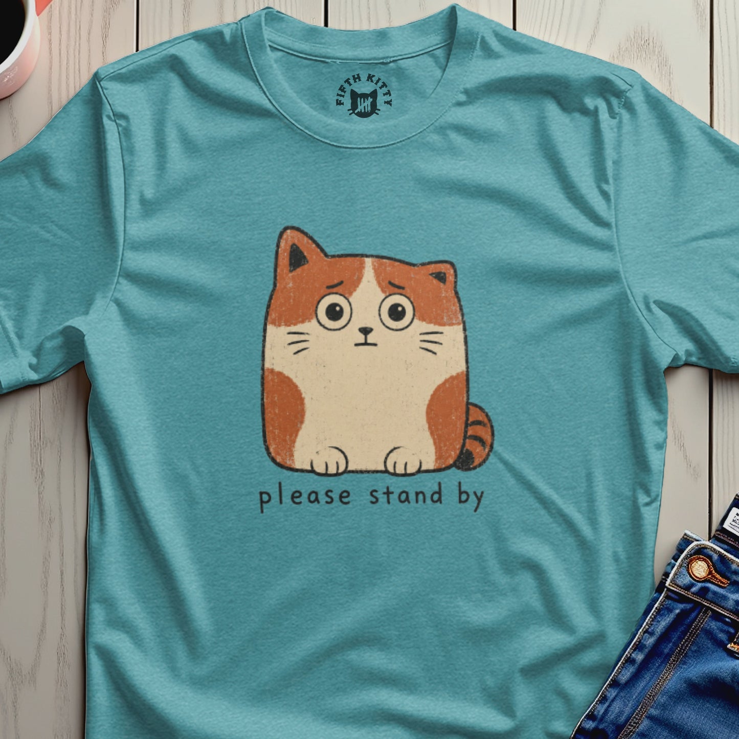 Teal t-shirt with a worried cartoon cat and "please stand by" text.