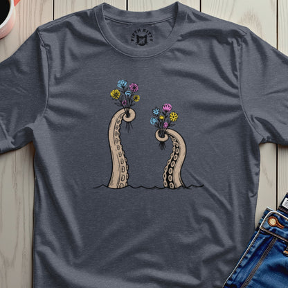 Tentacle arms holding bouquets of colorful flowers on a dark t-shirt.