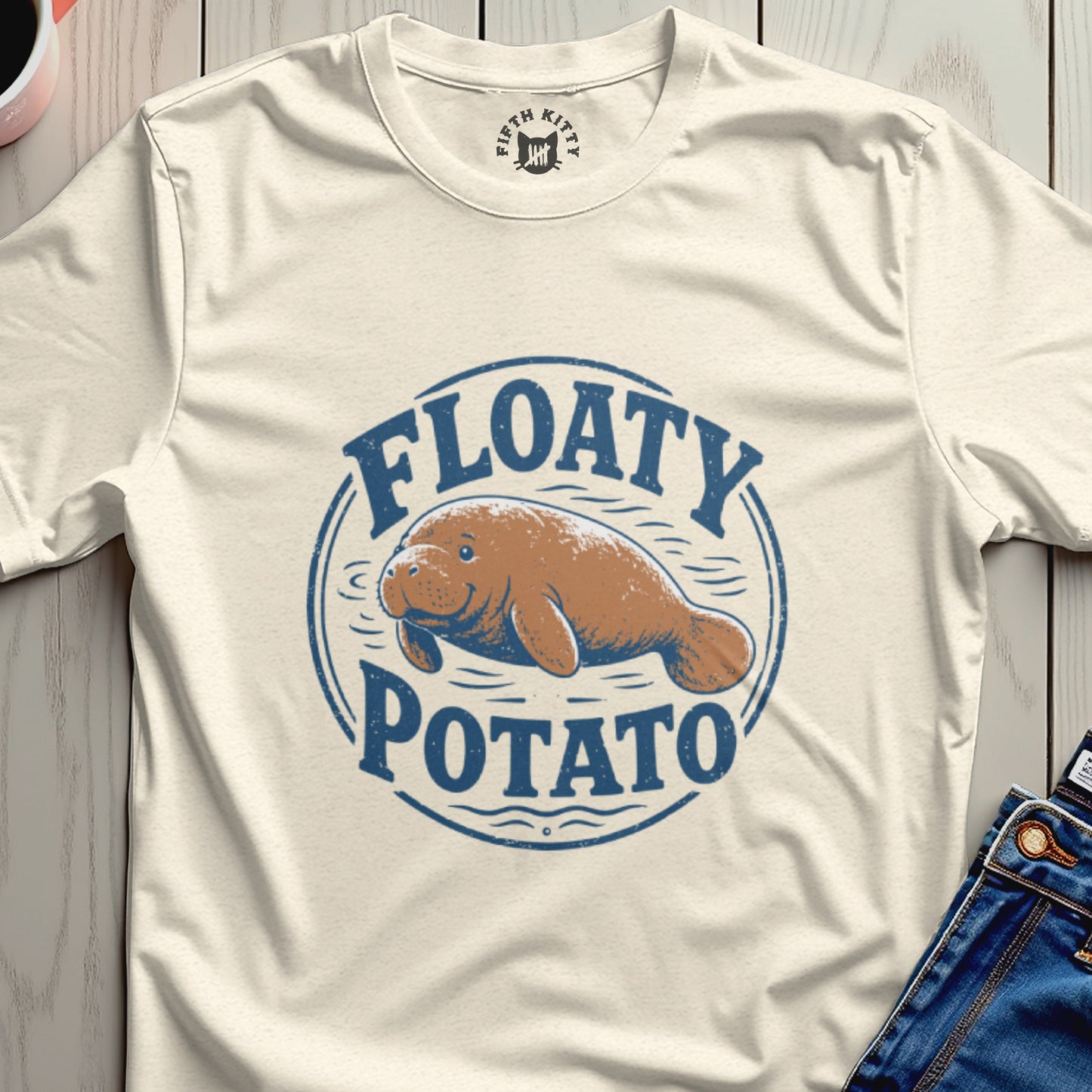 Cream t-shirt with a blue circular graphic of a smiling manatee above the words "FLOATY POTATO."