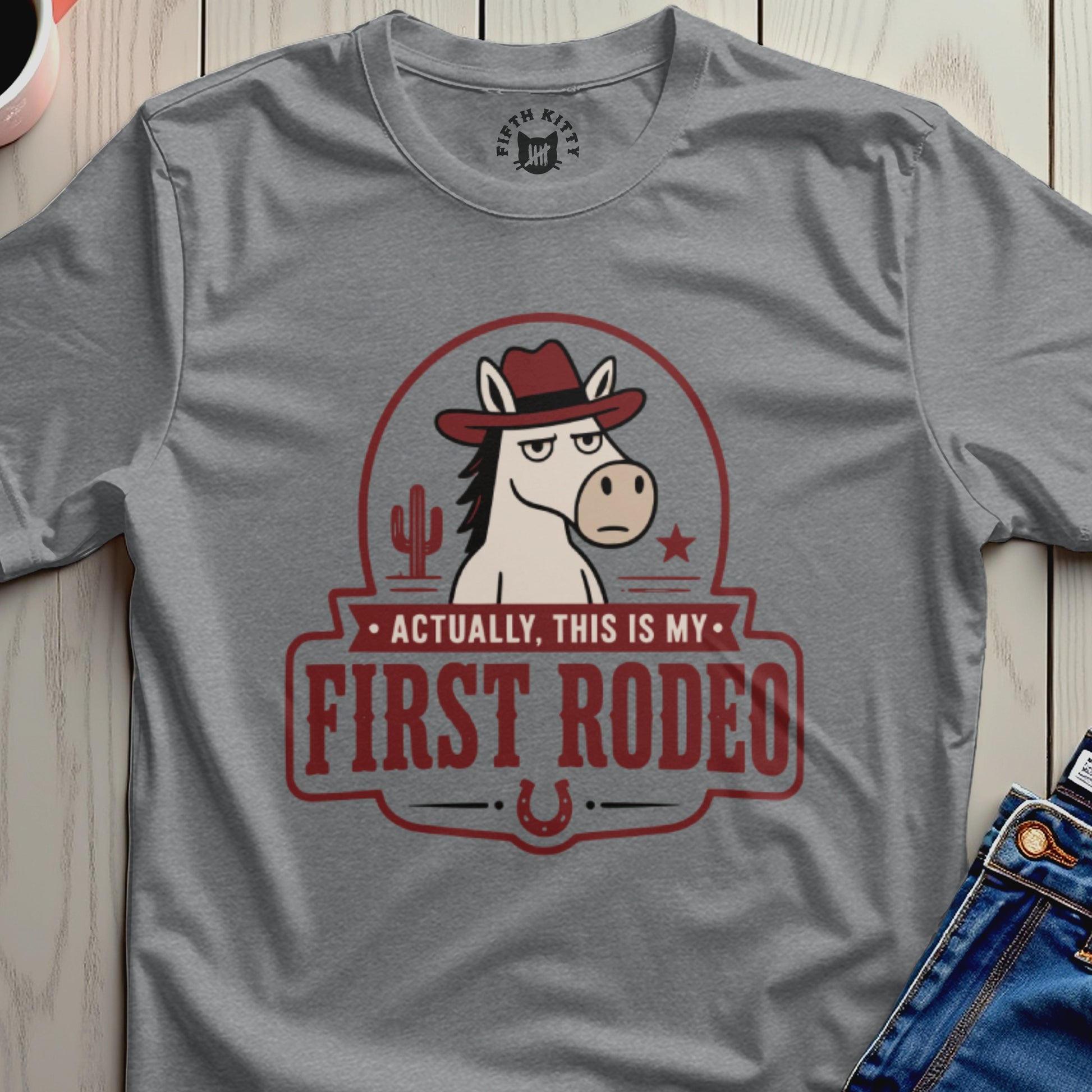 Grey t-shirt with a cartoon horse wearing a cowboy hat and text "Actually, This Is My First Rodeo".