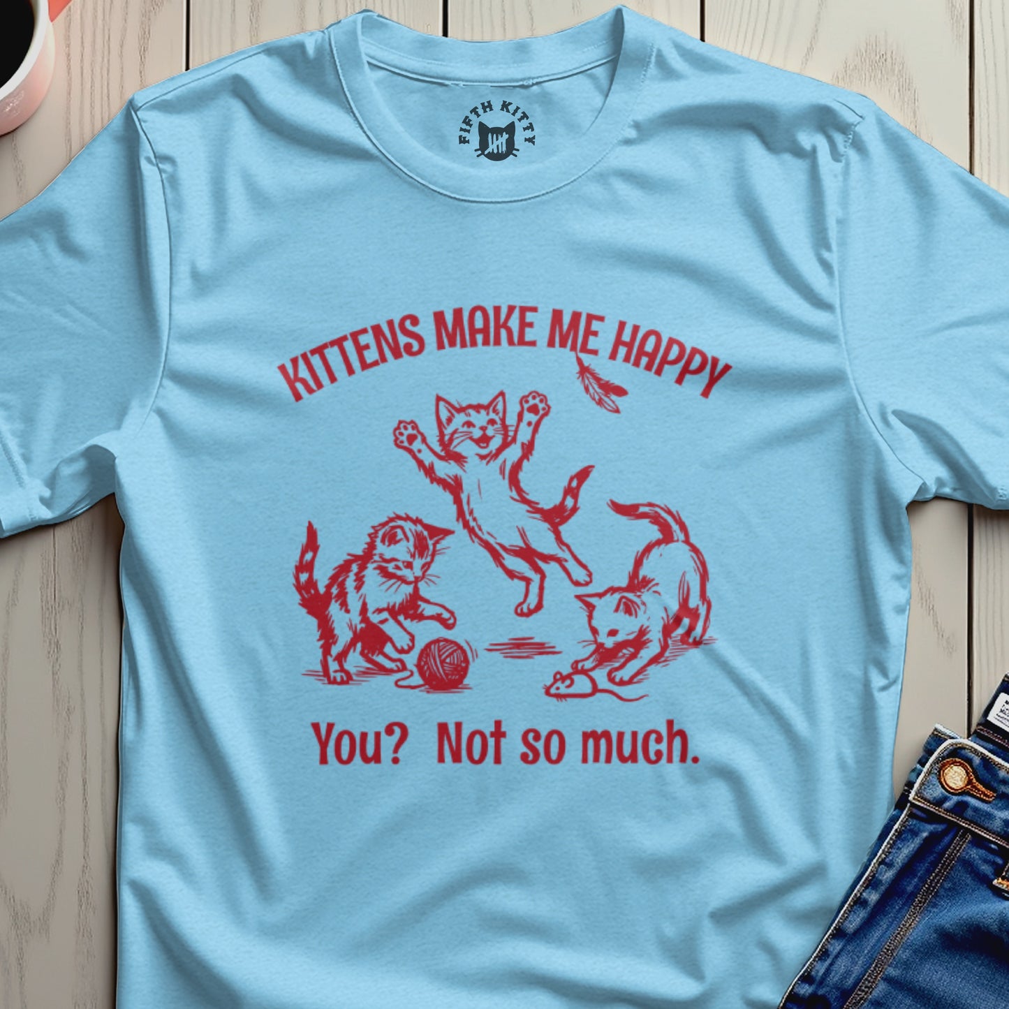 Light blue t-shirt with red text and graphic of three playful kittens.