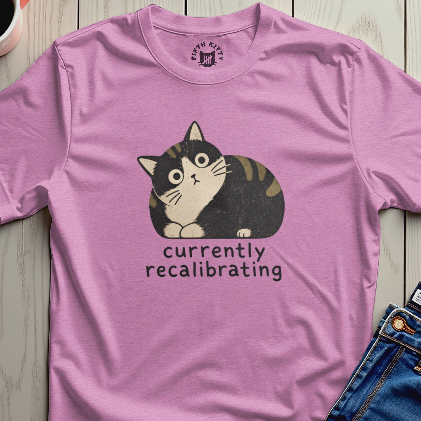 Pink t-shirt with a distressed graphic of a cat and text "currently recalibrating".