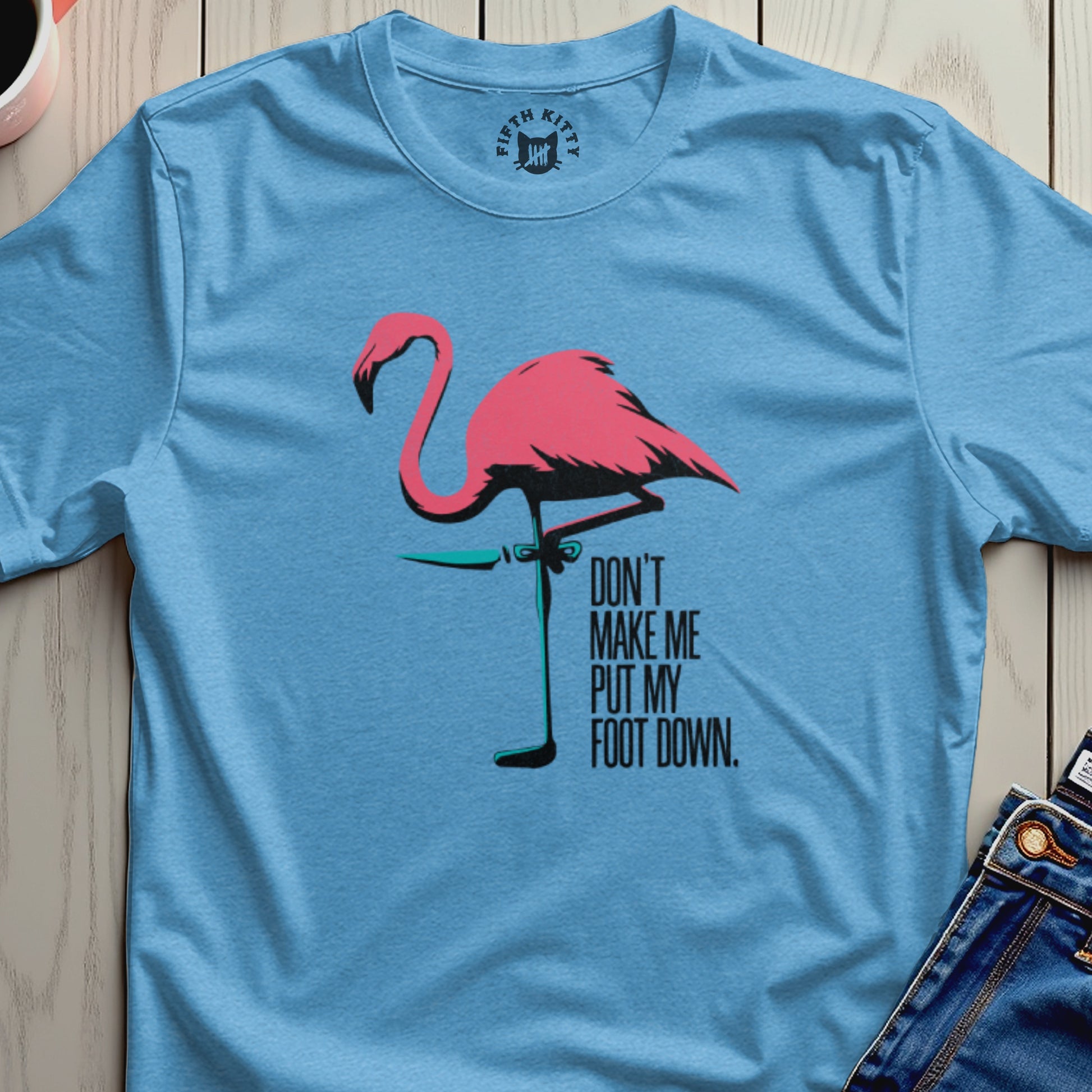 Light blue t-shirt with a pink flamingo and text Don't Make Me Put My Foot Down.