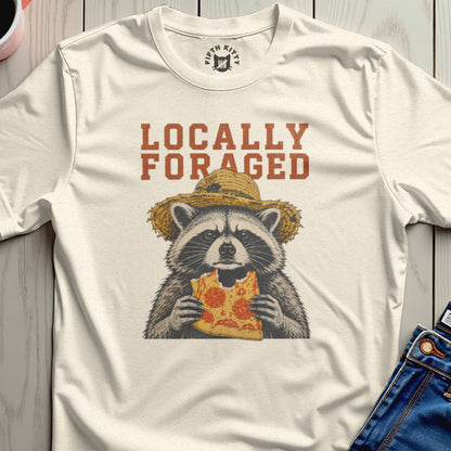 T-shirt with raccoon wearing straw hat eating pizza, text "Locally Foraged".