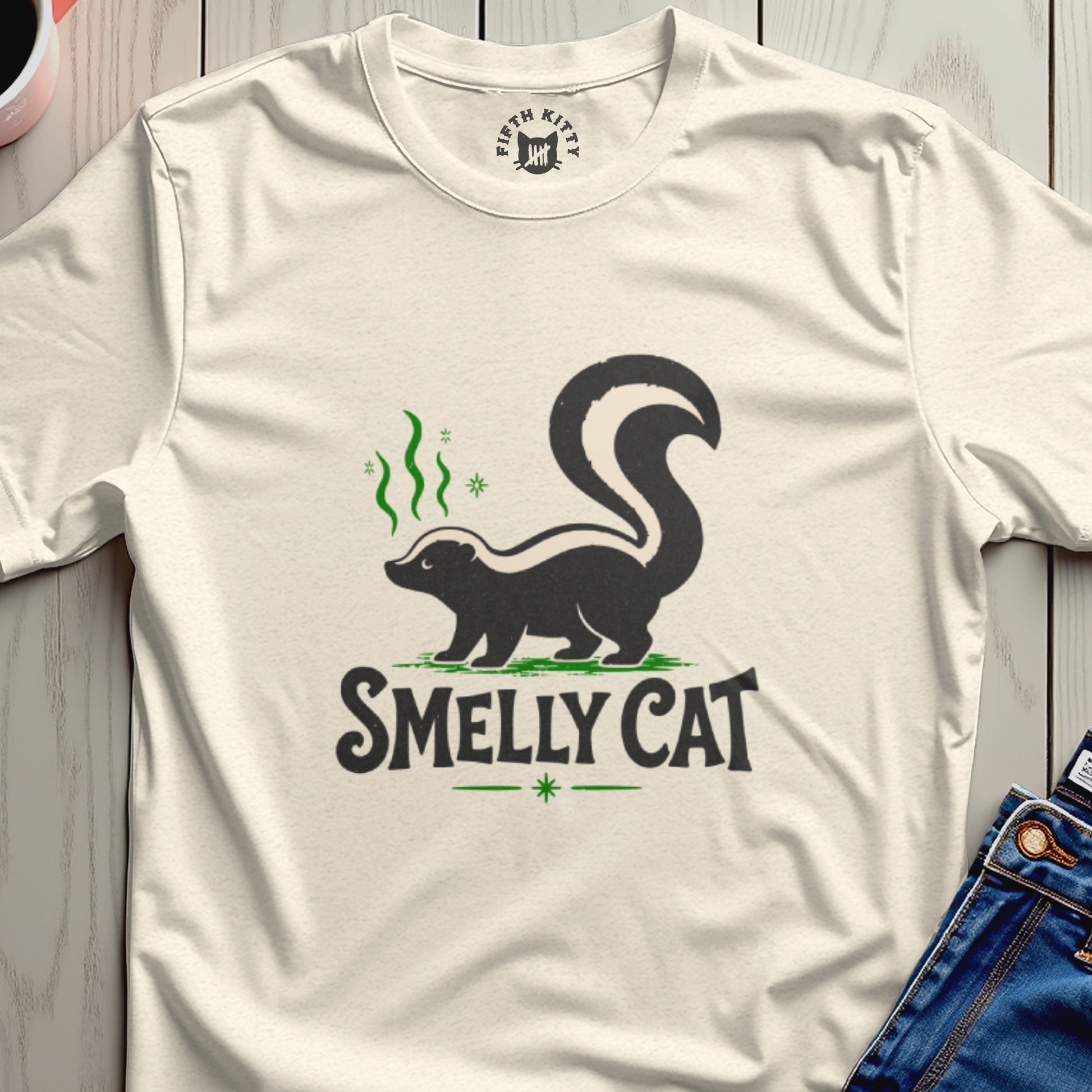 Cream t-shirt with black skunk graphic and "SMELLY CAT" text.